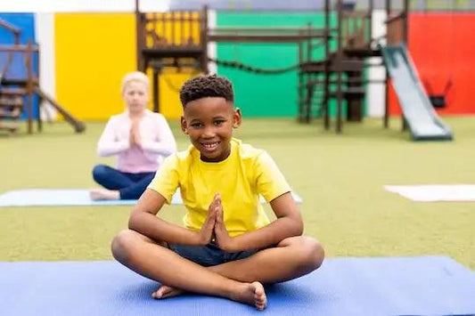 A group of students engaged in a mindfulness activity, sitting cross-legged on yoga mats in a colorful indoor gymnasium.